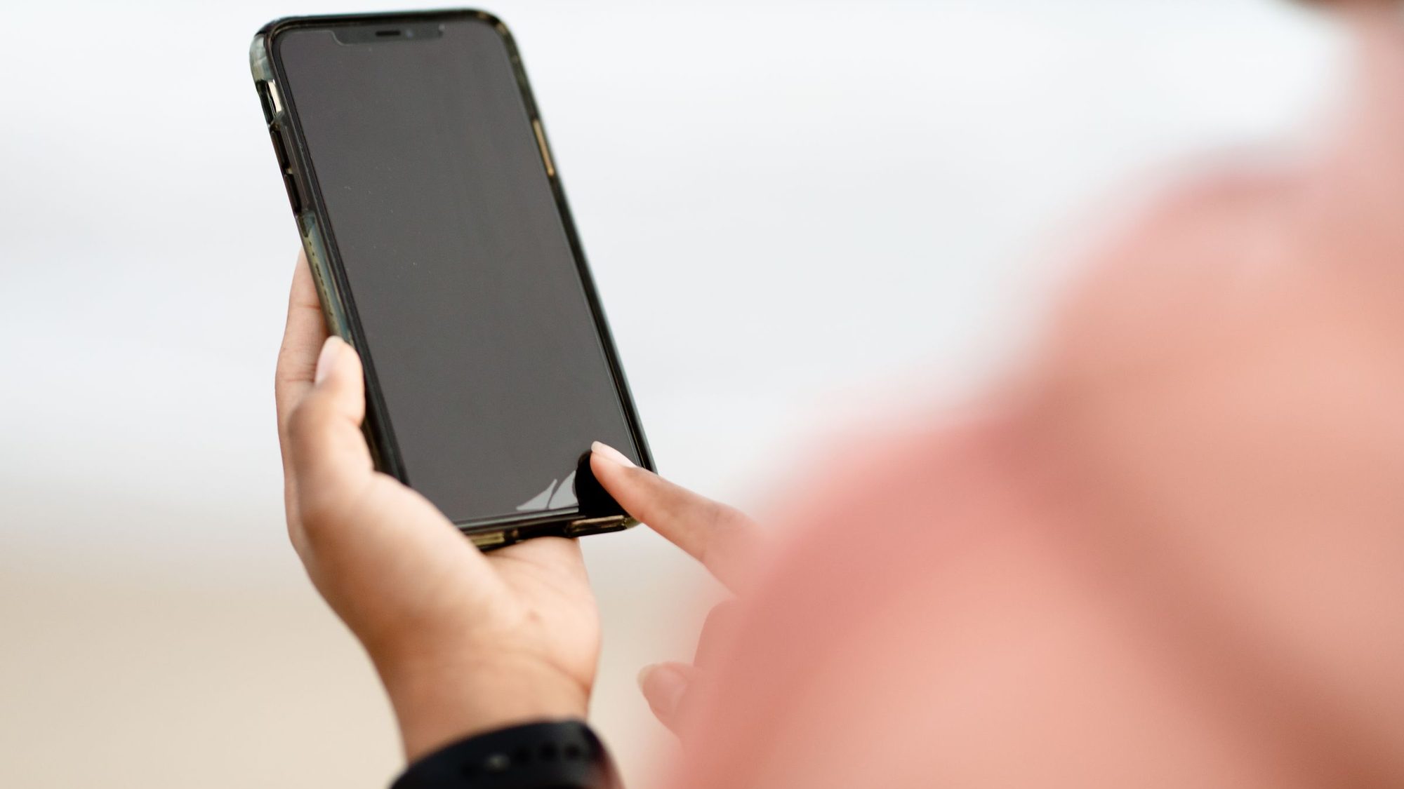 A hand holds a smartphone and taps the screen