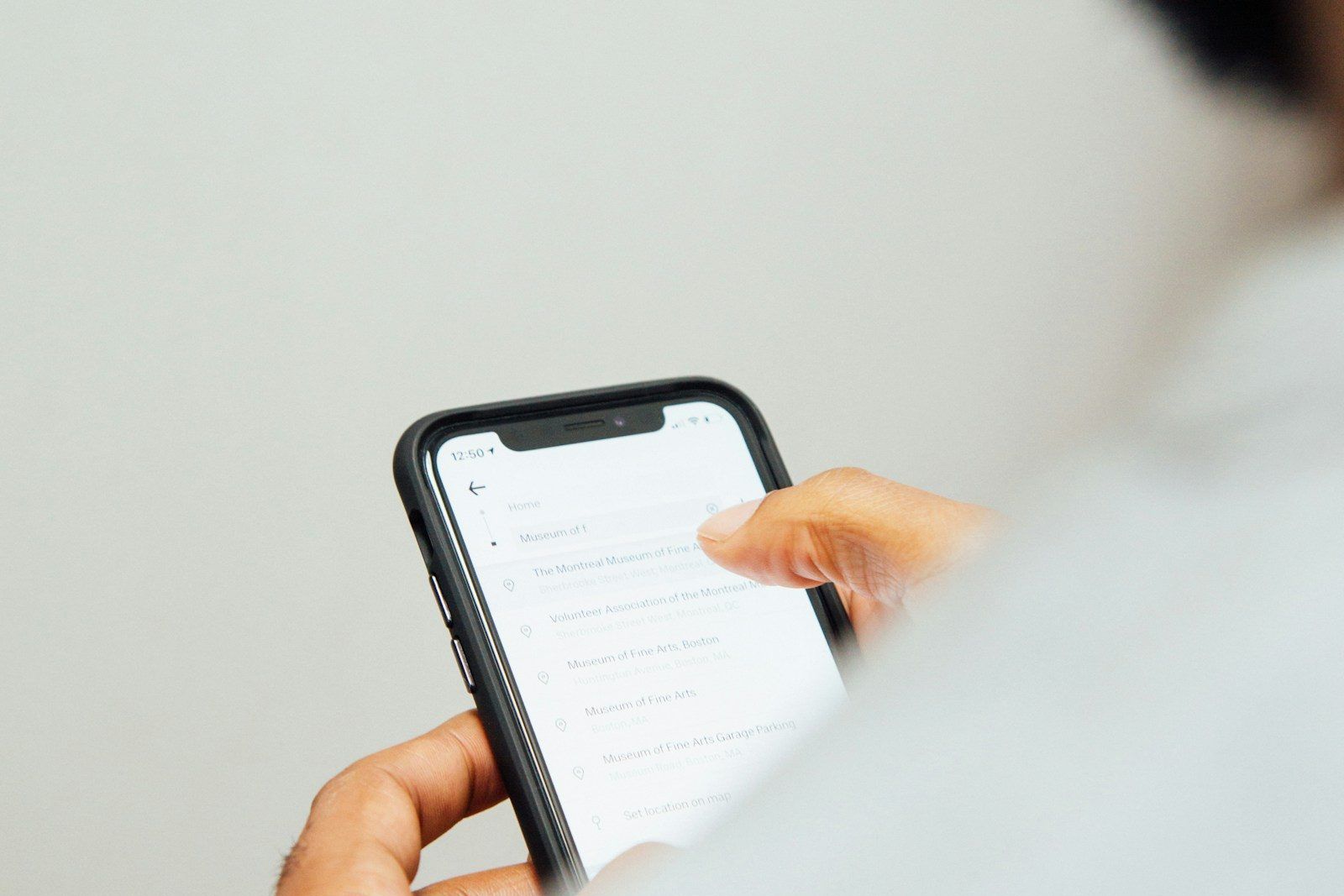 A hand holds a smartphone, one thumb on the screen