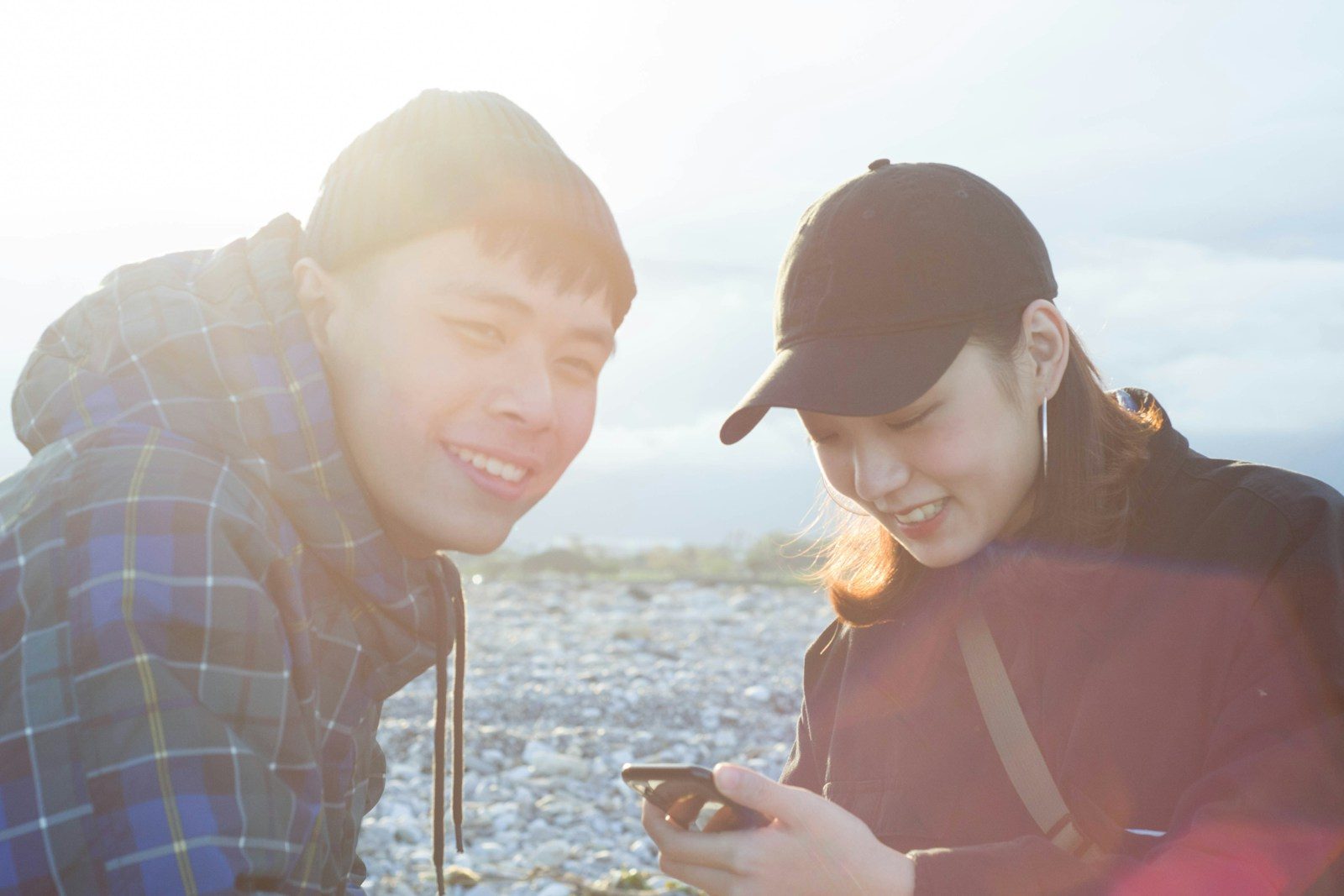 Two people outdoors look at a phone together