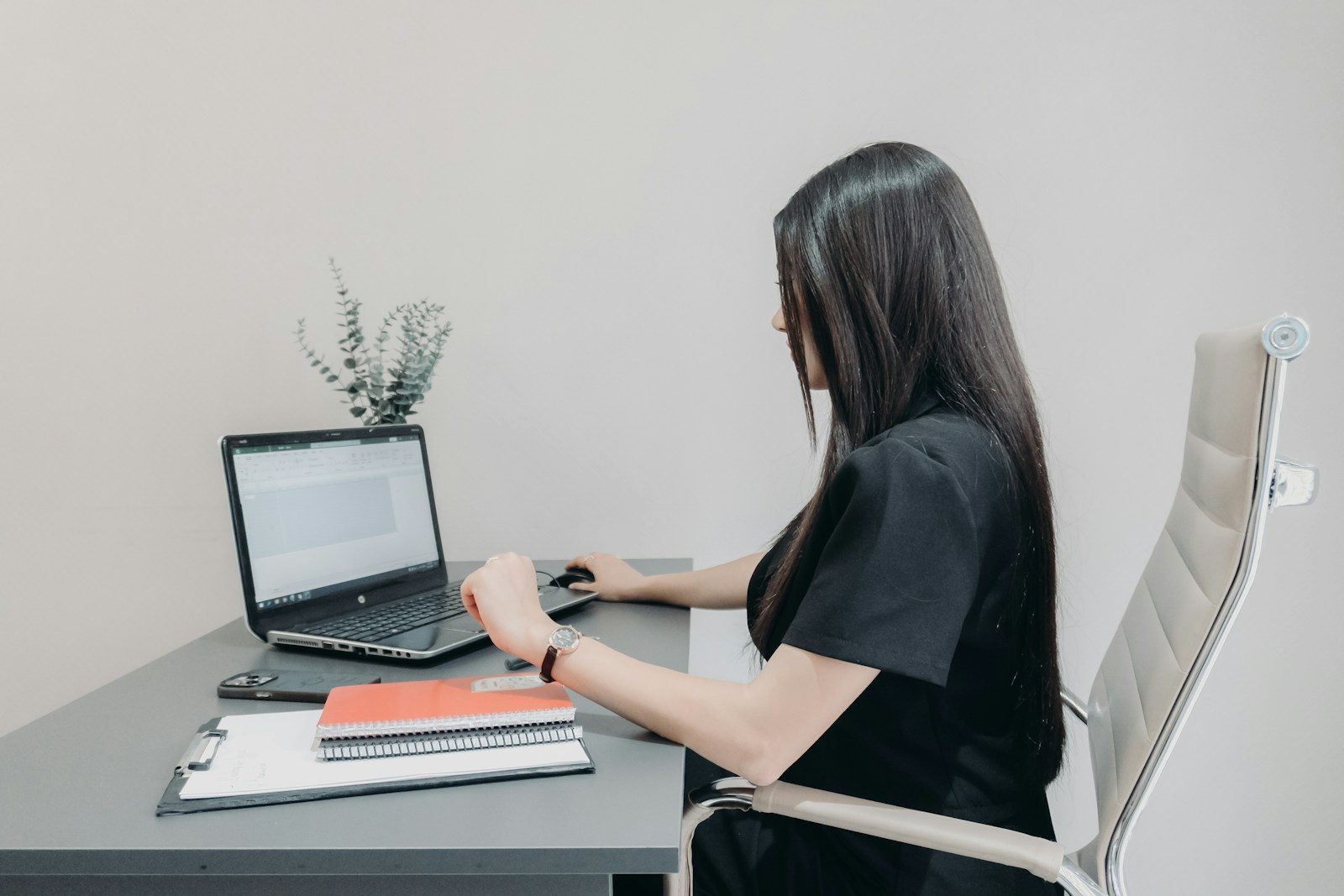 A woman works at a laptop at a tidy desk